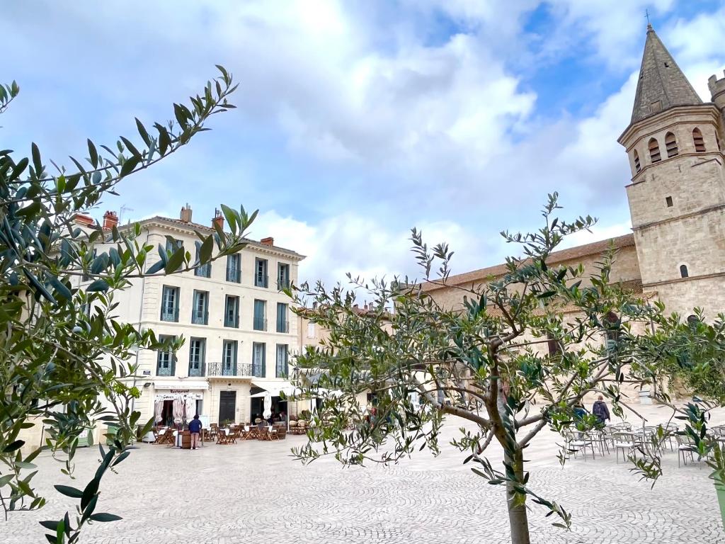 a building with a tower and a tree in a courtyard at L&#39;appart du galeriste 85m2 amazing view and space in Béziers