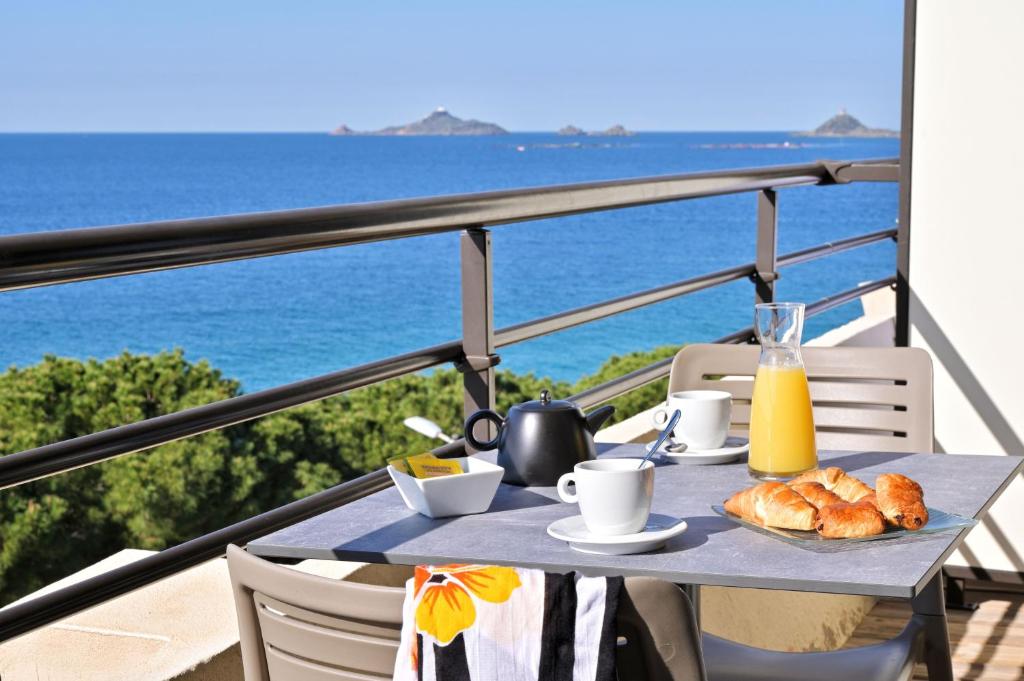 una mesa con desayuno en un balcón con vistas al océano en Résidence Les Calanques en Ajaccio