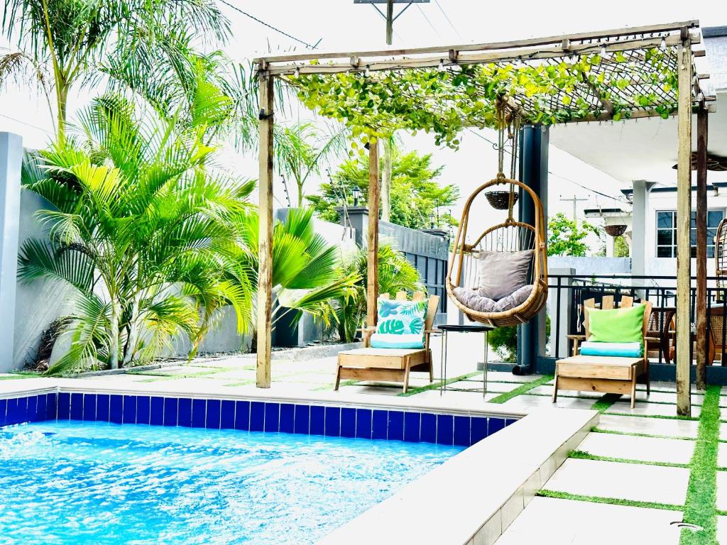 a patio with chairs and a swing next to a swimming pool at Ultraluxurious HolidayVilla with an Infinity Pool in Apenkwa