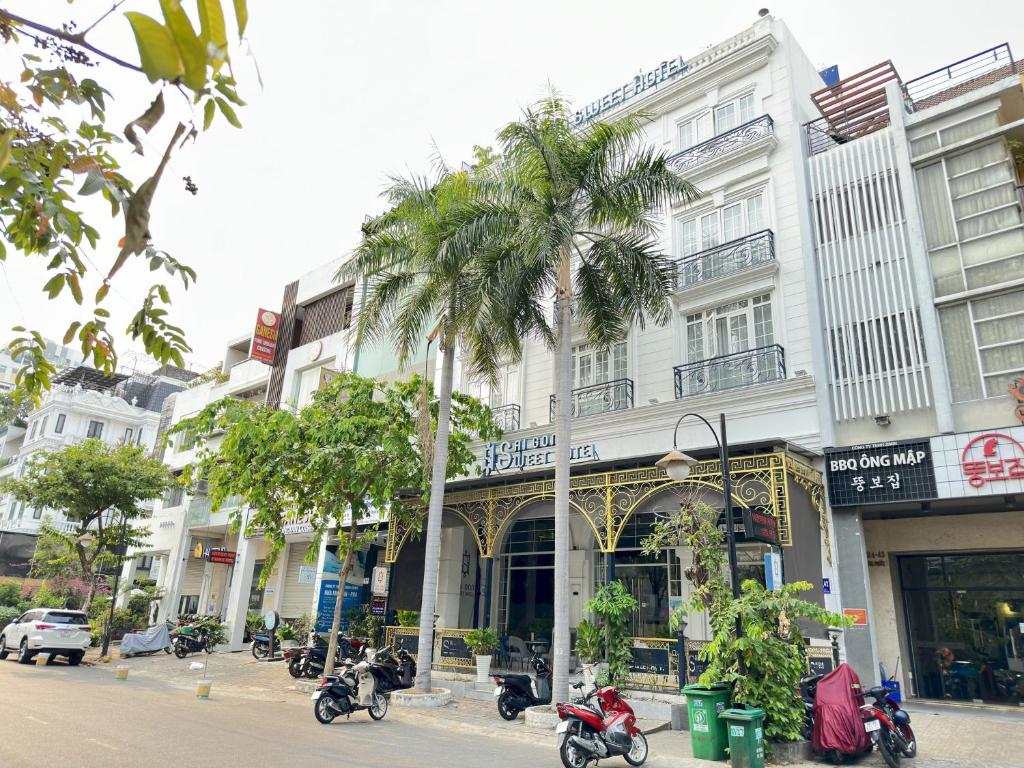 a palm tree in front of a building with motorcycles at Capital O 1177 Saigon Sweet Hotel in Ho Chi Minh City