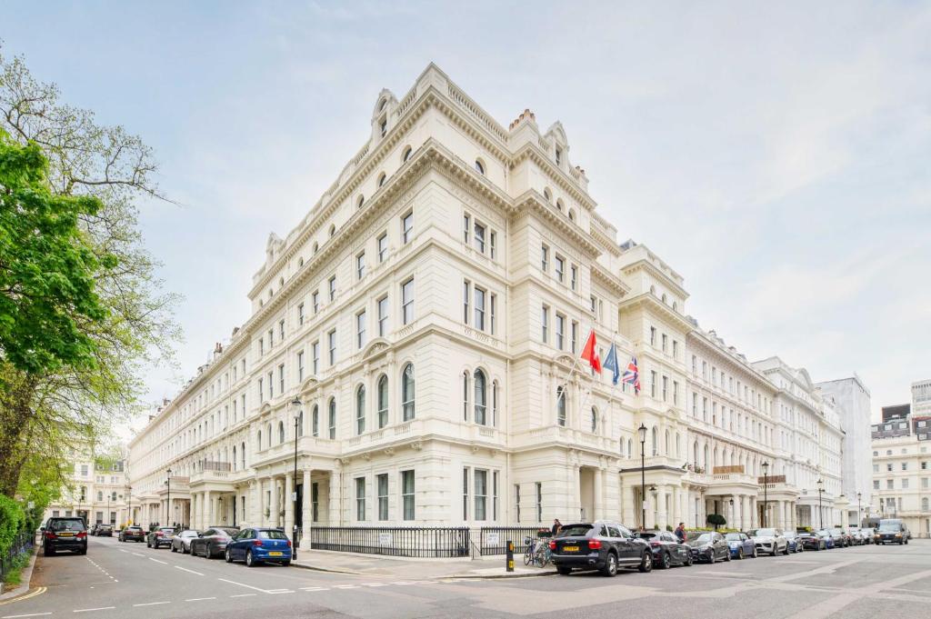 倫敦的住宿－Elegant Art Deco whole apartment 2mins to Hyde Park, 8mins to Bayswater, Nottinghill, Paddington，一座白色的大建筑,前面有汽车停放