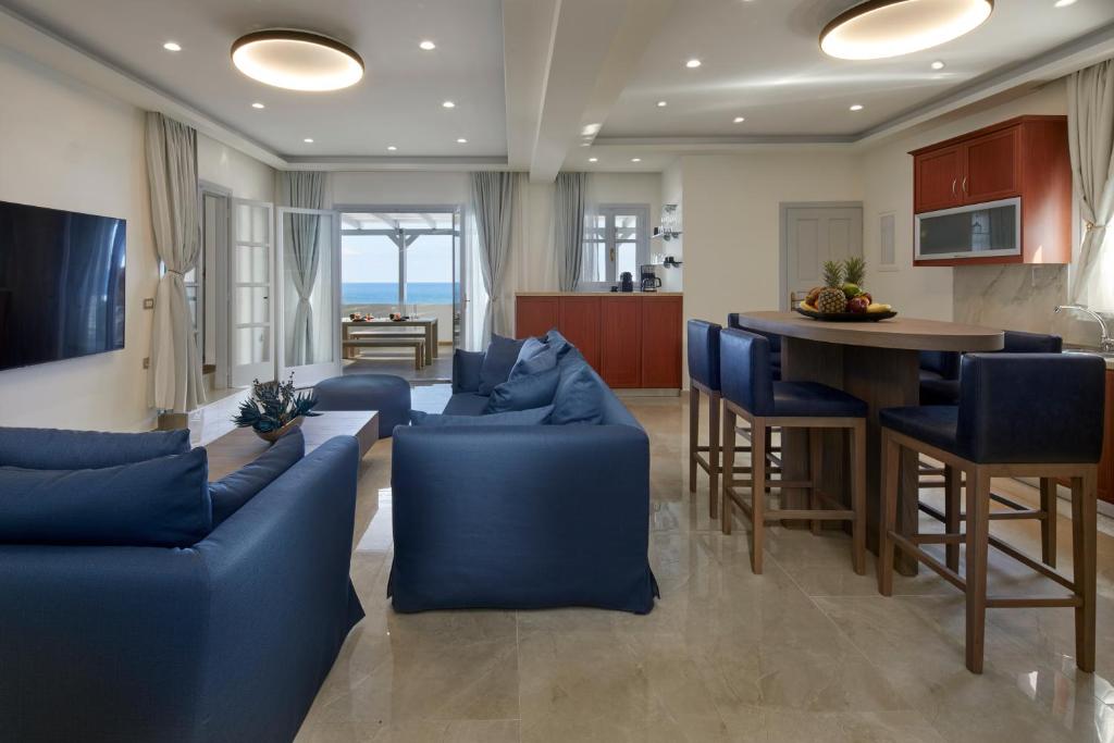 a living room with blue couches and a kitchen at Soultouch Beachfront Villa in Perissa