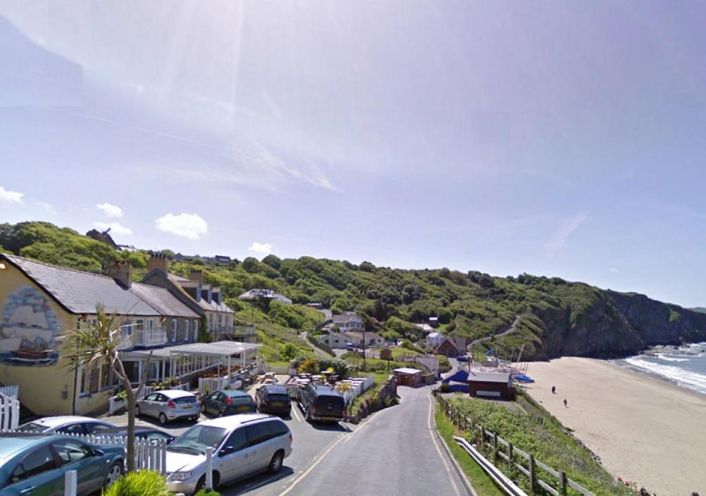 a small town with cars parked on a road next to the beach at Cilie Tresaith in Penbryn