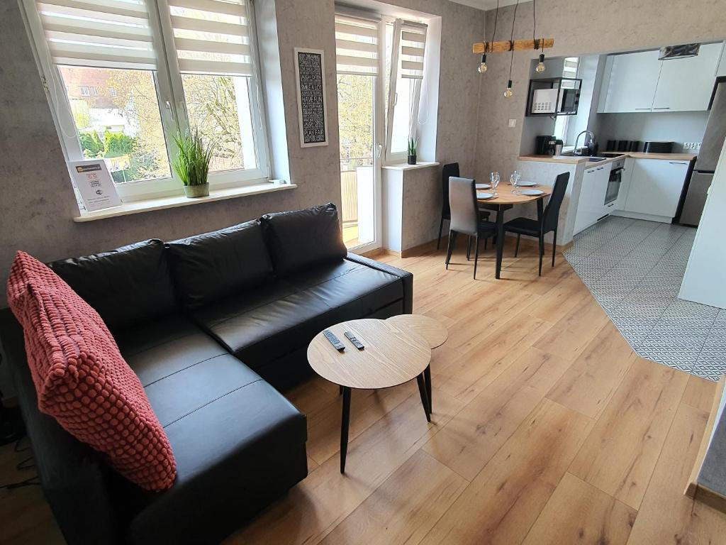 a living room with a black couch and a table at JDK Apartamenty Legionów 32m2 4-osobowy in Kalisz