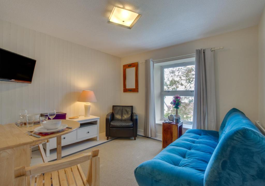uma sala de estar com um sofá azul e uma mesa em Eluned Tresaith em Penbryn