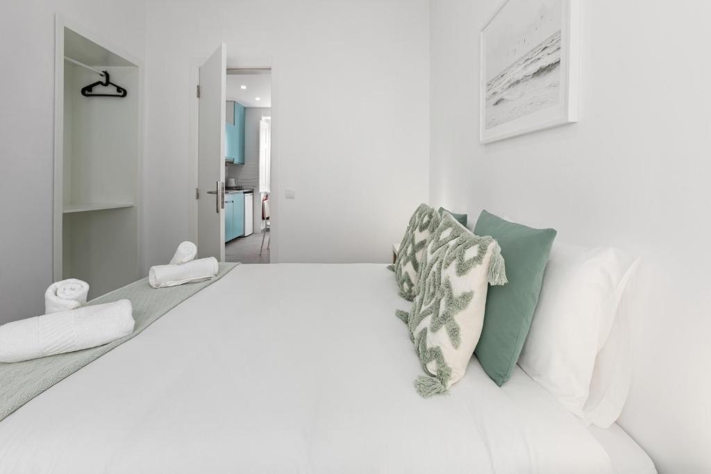 a white bedroom with a large bed with pillows at Refúgio da Nazaré in Nazaré