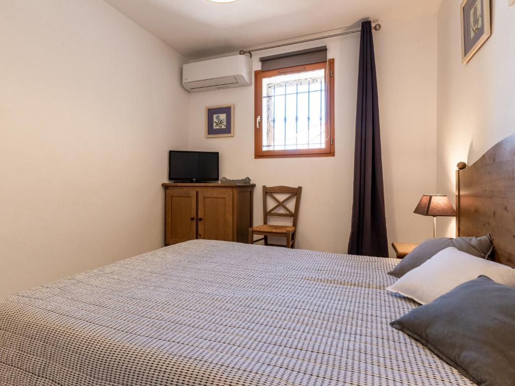 a bedroom with a bed and a tv and a window at Holiday Home Chez Béatrice et Pascal by Interhome in Belgodère