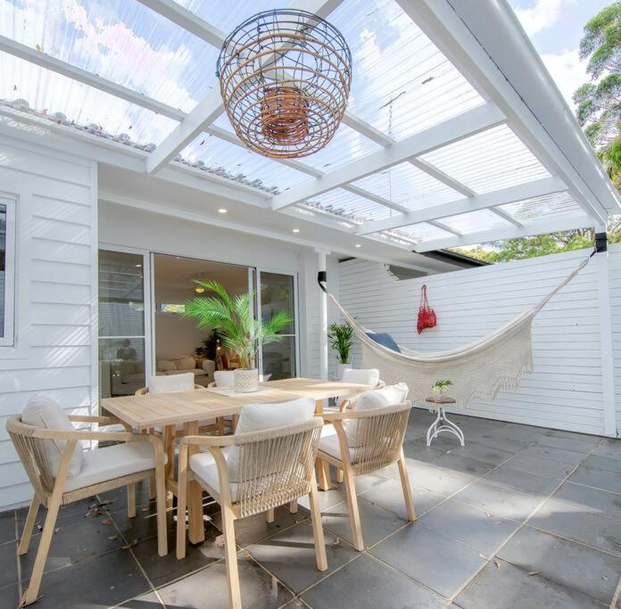 a patio with a table and chairs and a hammock at SALTY SNOOZE - Your Coastal Holiday House in Avalon