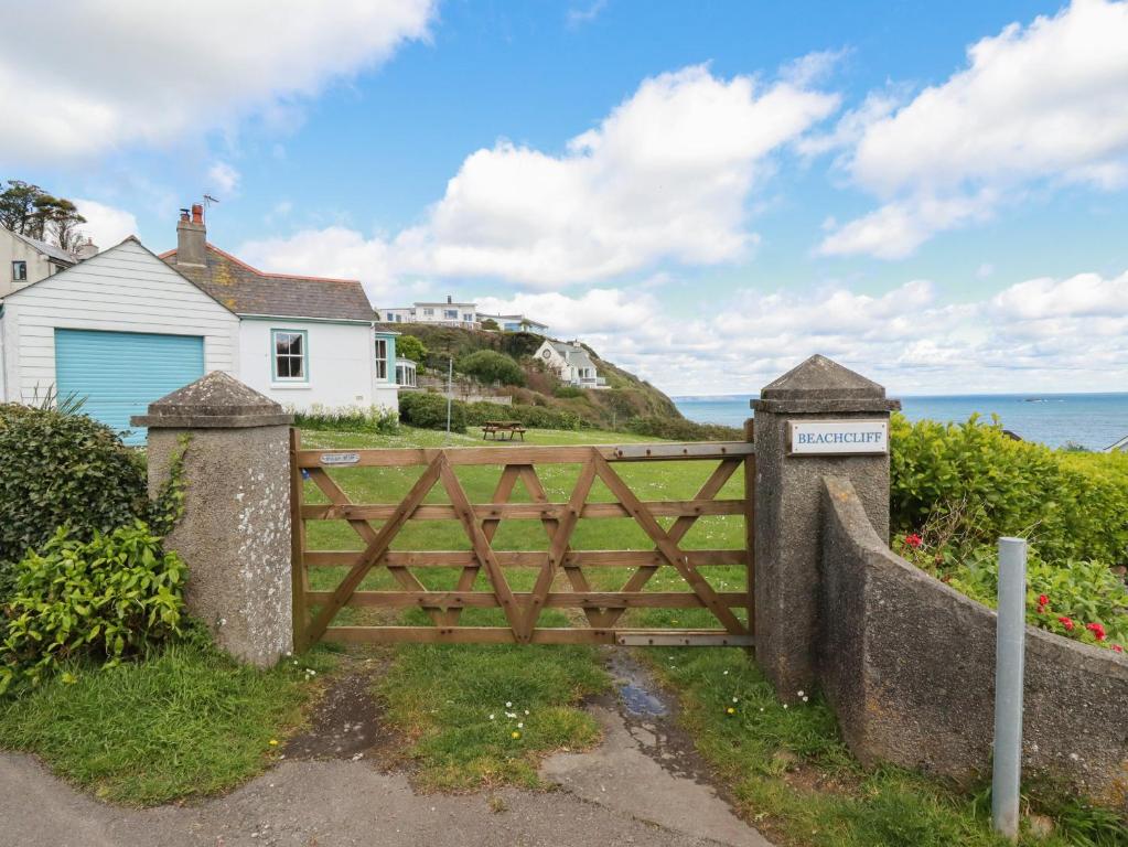 a wooden gate in front of a house and the ocean at Beachcliff in Gorran Haven