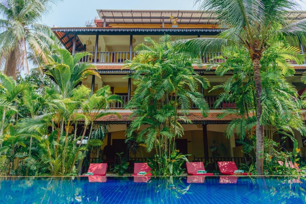 um hotel com palmeiras e uma piscina em Pandora Suite D'Angkor em Siem Reap