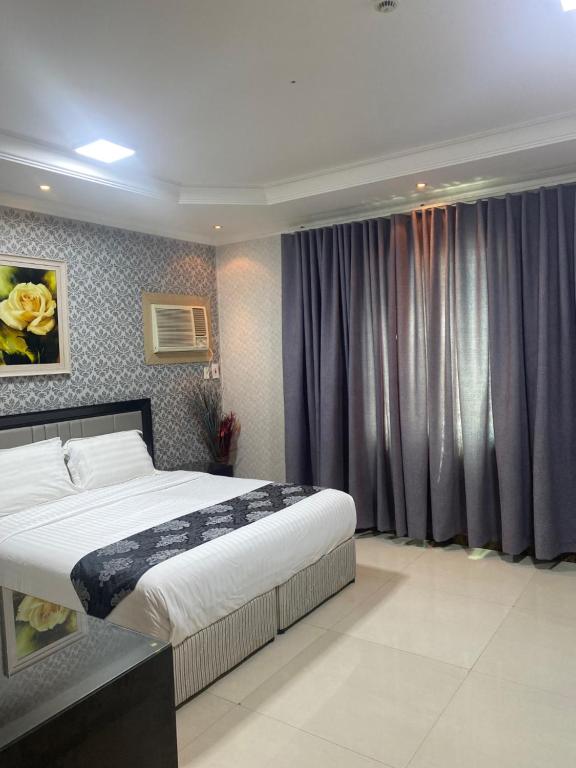 Jubail High Rise Hotel في الجبيل: غرفة نوم بسرير كبير وستائر ارجوانية
