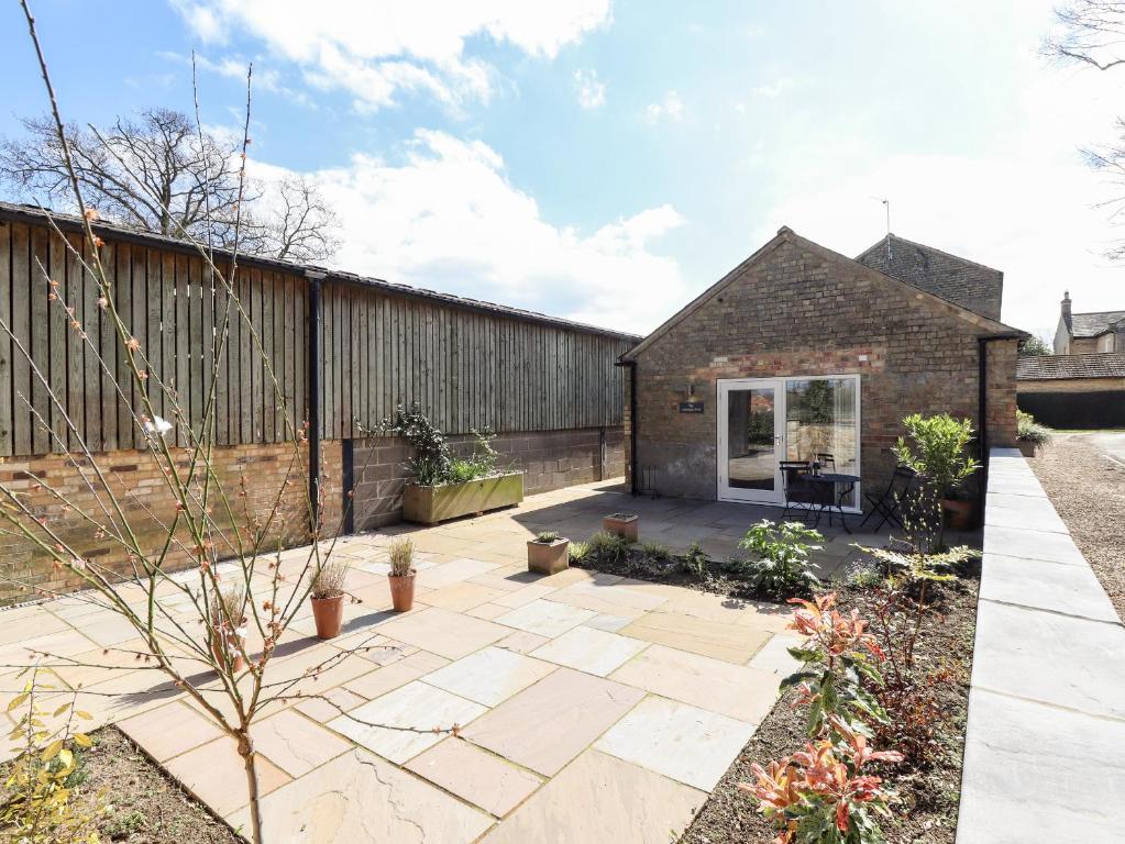 a garden with a patio and a brick building at The Asparagus Shed in Sleaford