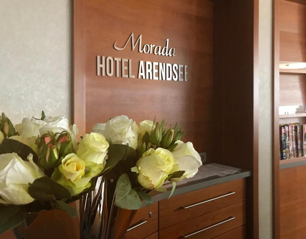 a bunch of white roses in a vase in a room at Morada Hotel Arendsee in Kühlungsborn
