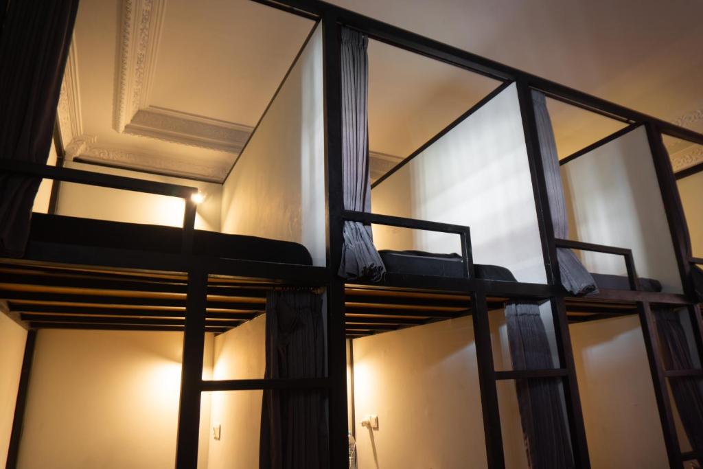 two bunk beds in a room with windows at Sunshot Hostel in Legian