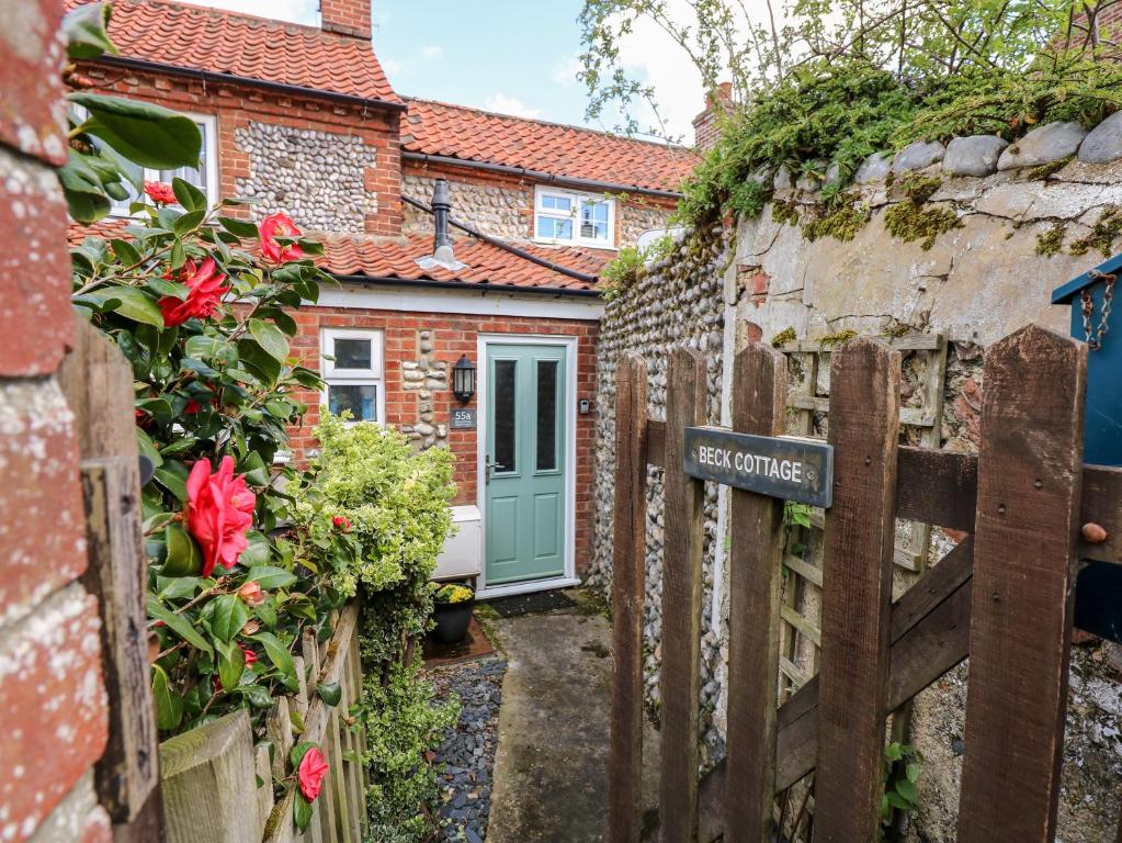 a gate to a brick house with a blue door at Beck Cottage in Sheringham