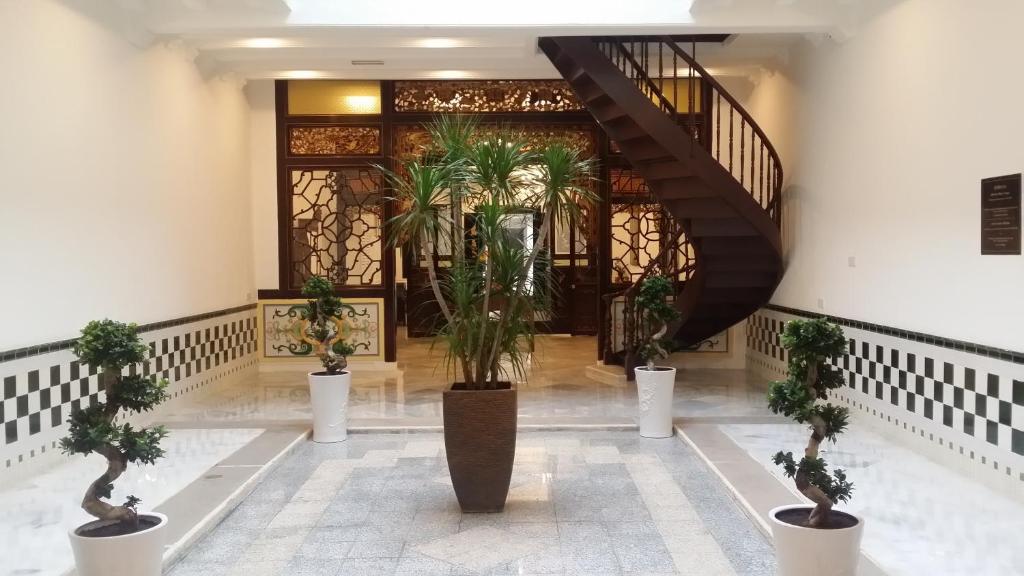 a lobby with potted plants and a staircase at Heeren Palm Suites in Melaka