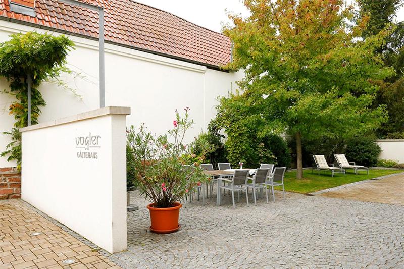 a patio with a table and chairs next to a building at Gästehaus Vogler in Heuchelheim-Klingen