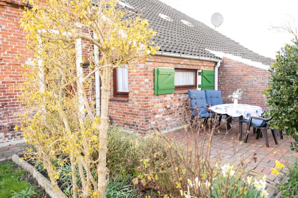 a patio with a table and chairs in front of a brick house at Sophienmühle II Nähe Carolinensiel in Wangerland
