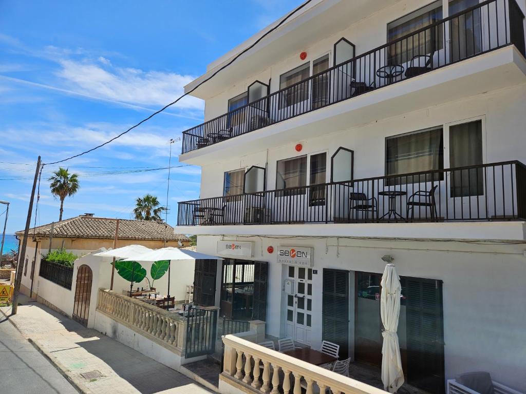 un edificio bianco con patio e ombrellone di SEVEN Hostal a Cala Millor