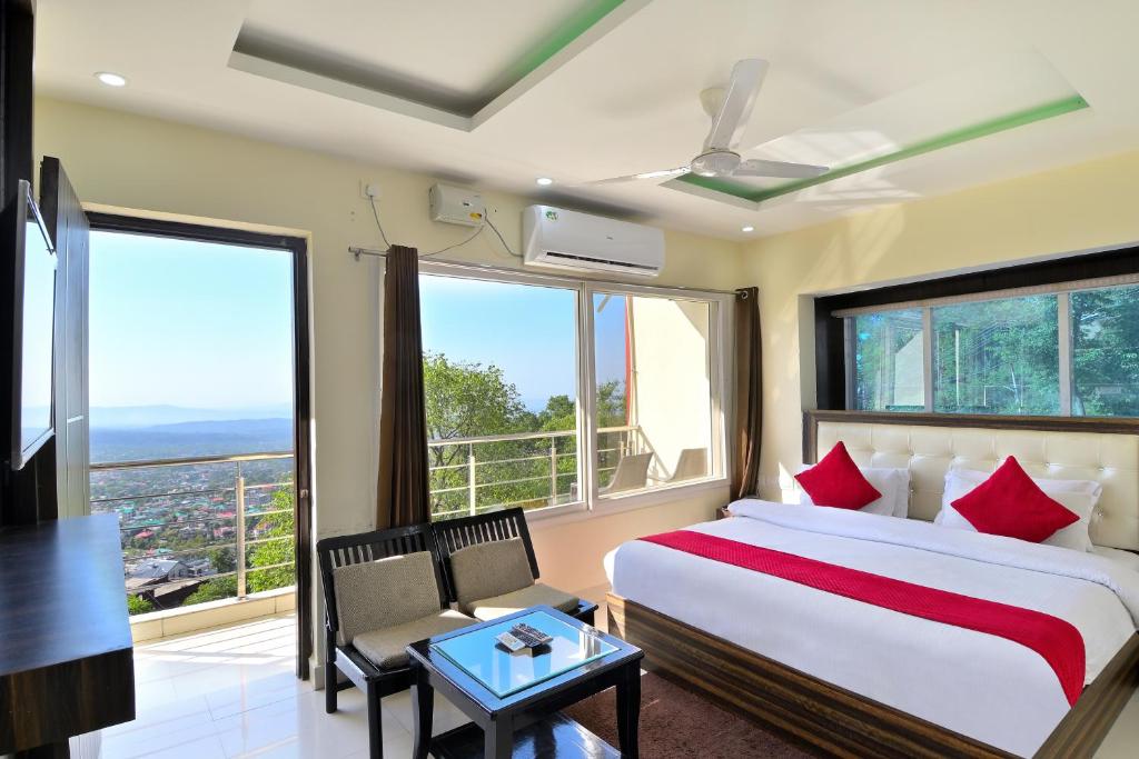 a bedroom with a bed and a large window at LA Riqueza Bliss Valley Mall Road - Beautiful View of Mountains in Dharamshala