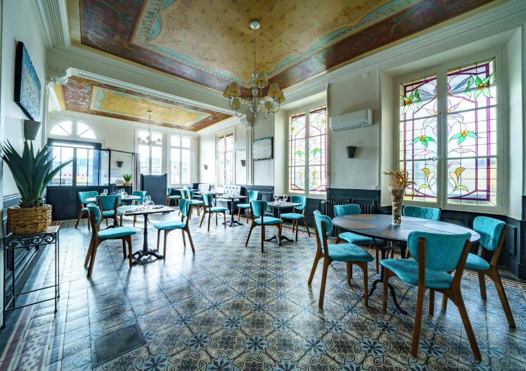 un comedor con mesas, sillas y ventanas en Logis Le Grand Hotel, en Château-du-Loir
