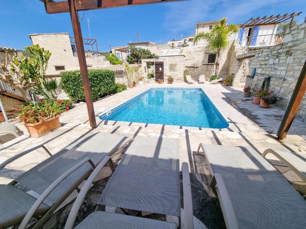 a villa with a swimming pool and chairs at Aphrodite's Pool Retreat in Skarinou