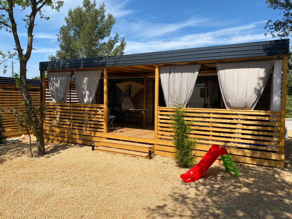 une maison en bois avec un objet rouge devant elle dans l'établissement Mobile Home Saky, Camp Soline, à Biograd na Moru