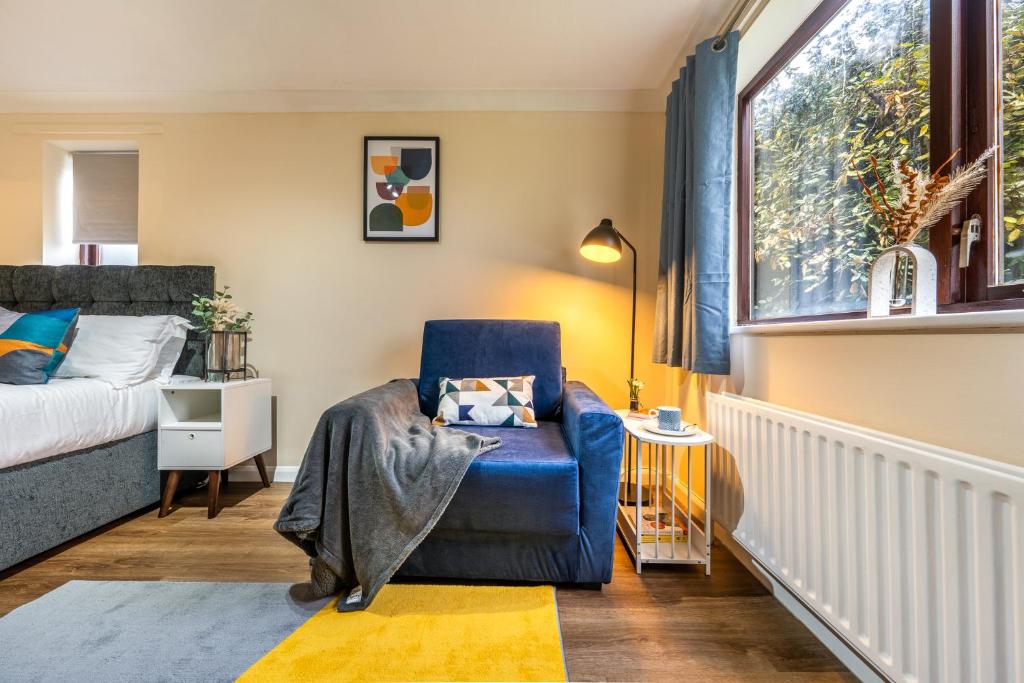 a bedroom with a blue chair and a window at Grange Studio Apartment - Heathrow in London