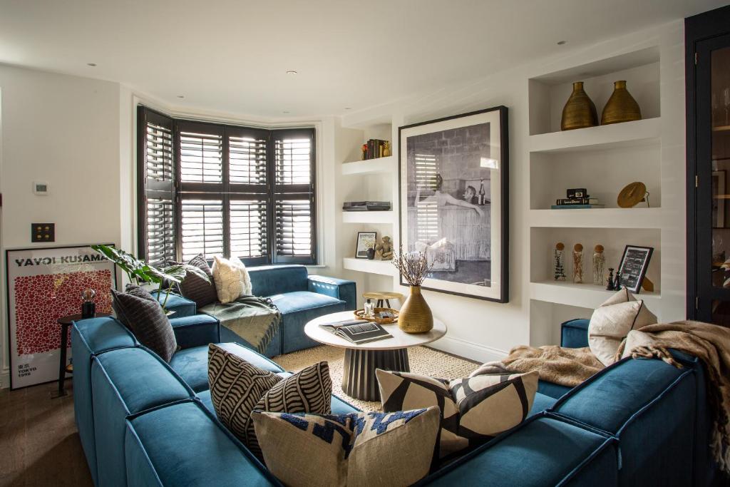 ein Wohnzimmer mit blauen Sofas und einem Tisch in der Unterkunft The Luxury Fulham Townhouse in London