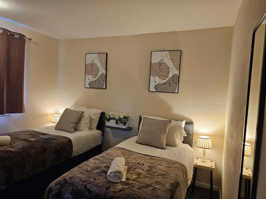 a hotel room with two beds and two lamps at Warm Contractor-Friendly Home in Luton