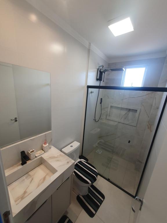 a bathroom with a shower and a toilet and a sink at Apartamento de Luxo com Piscina em Bombinhas in Bombinhas