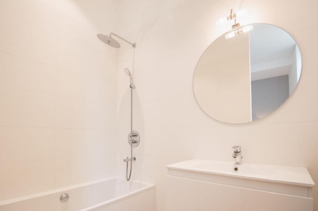 a white bathroom with a sink and a mirror at L&#39;appartement du Cellier in Pommard
