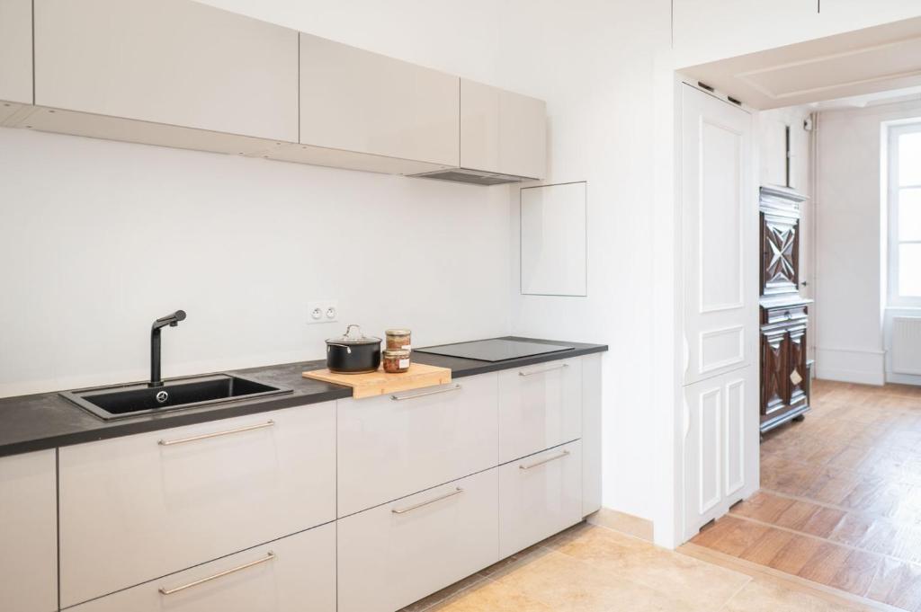 a white kitchen with white cabinets and a sink at L&#39;appartement du Cellier in Pommard