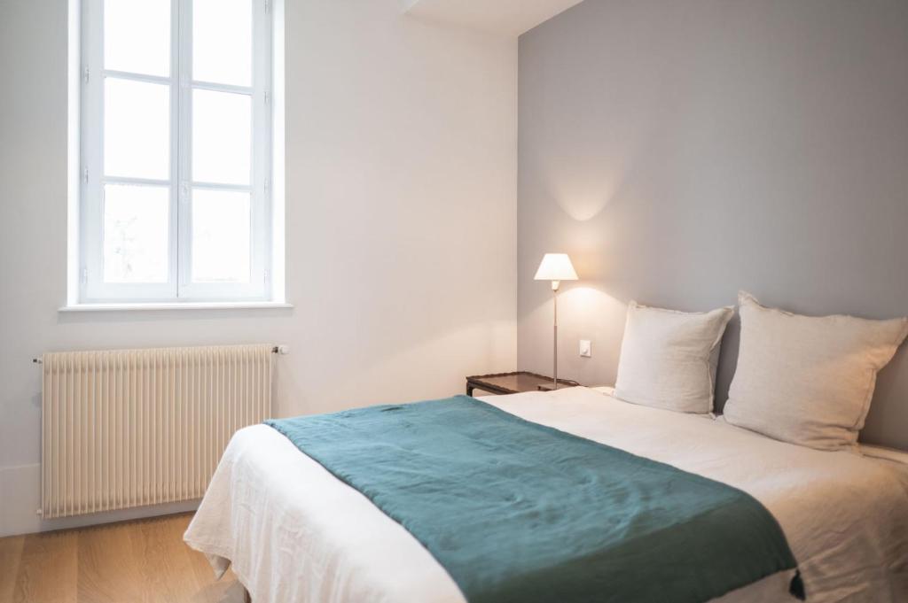 a bedroom with a large white bed and two windows at L&#39;appartement du Cellier in Pommard
