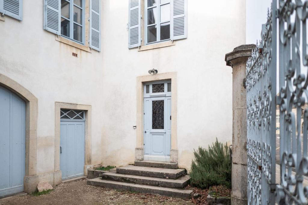 a white building with a blue door and stairs at L&#39;appartement du Cellier in Pommard