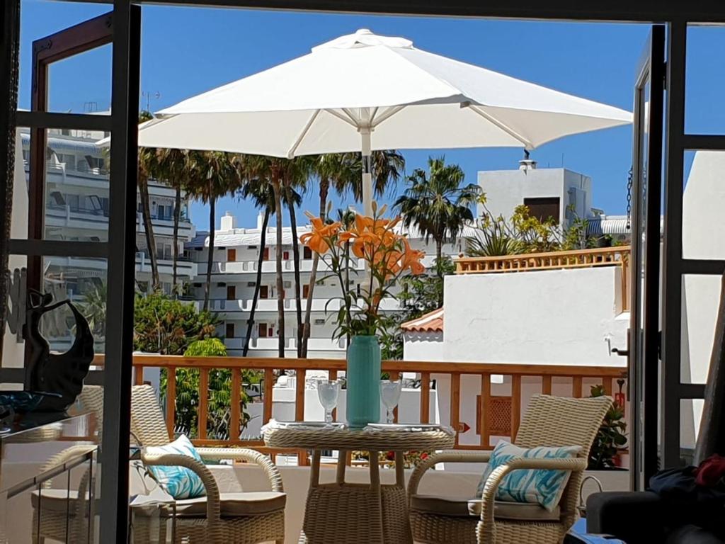 una mesa con una sombrilla blanca en el balcón en Costa Adeje Modern Studio, close to the beach en Adeje