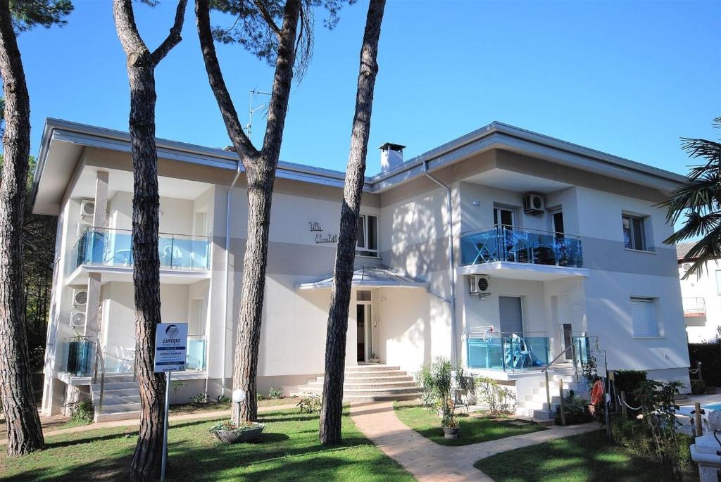 a white building with palm trees in front of it at Villa Elisabeth in Lignano Sabbiadoro