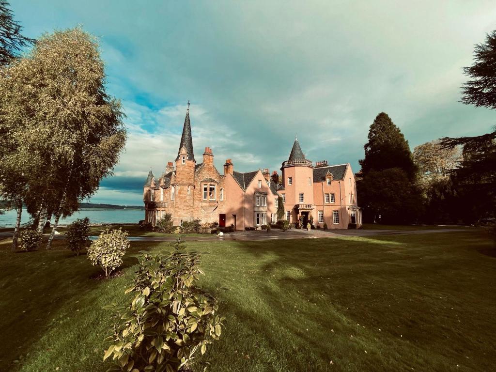 stary zamek na polu trawy z drzewem w obiekcie Bunchrew House Hotel w mieście Inverness