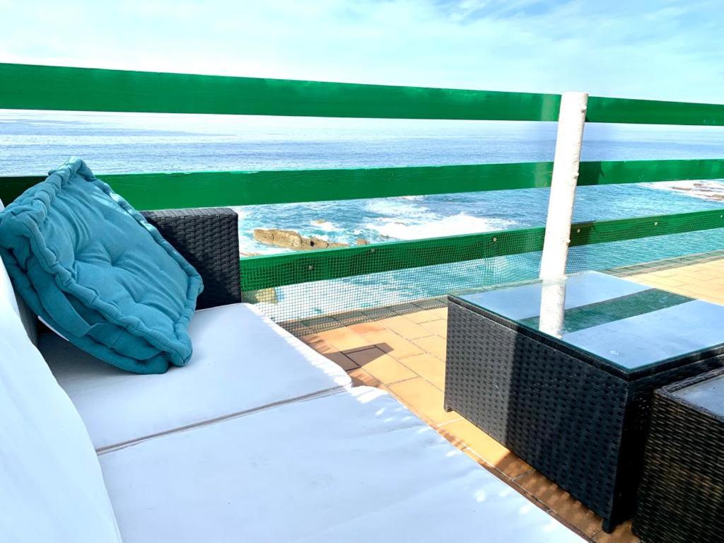 un sofá en un balcón con vistas al océano en LA TERRAZA DE PLAYA ESTAÑO, en Gijón