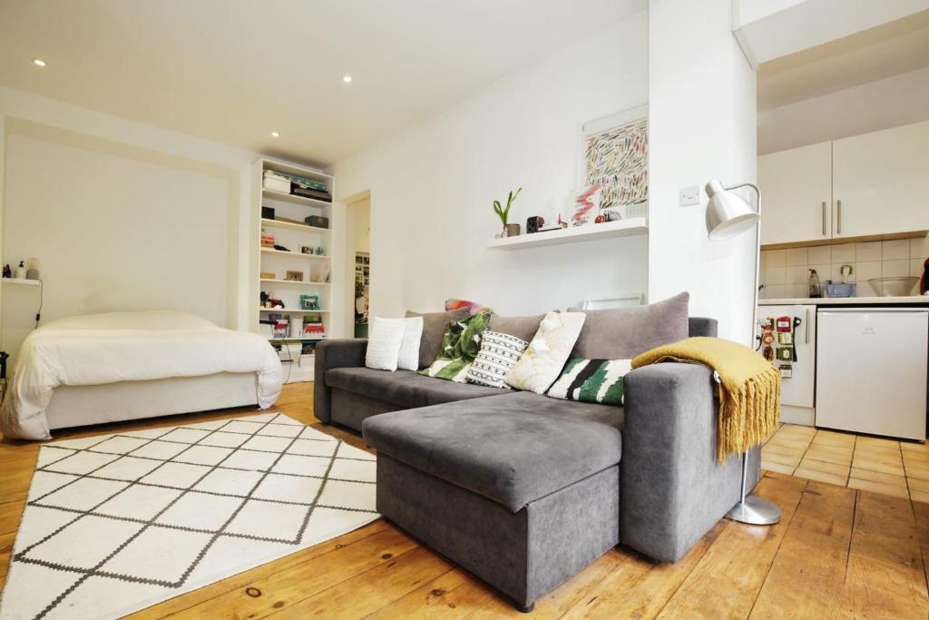 ein Wohnzimmer mit einem Sofa und einem Bett in der Unterkunft Charming West London Studio Your Urban Oasis in London