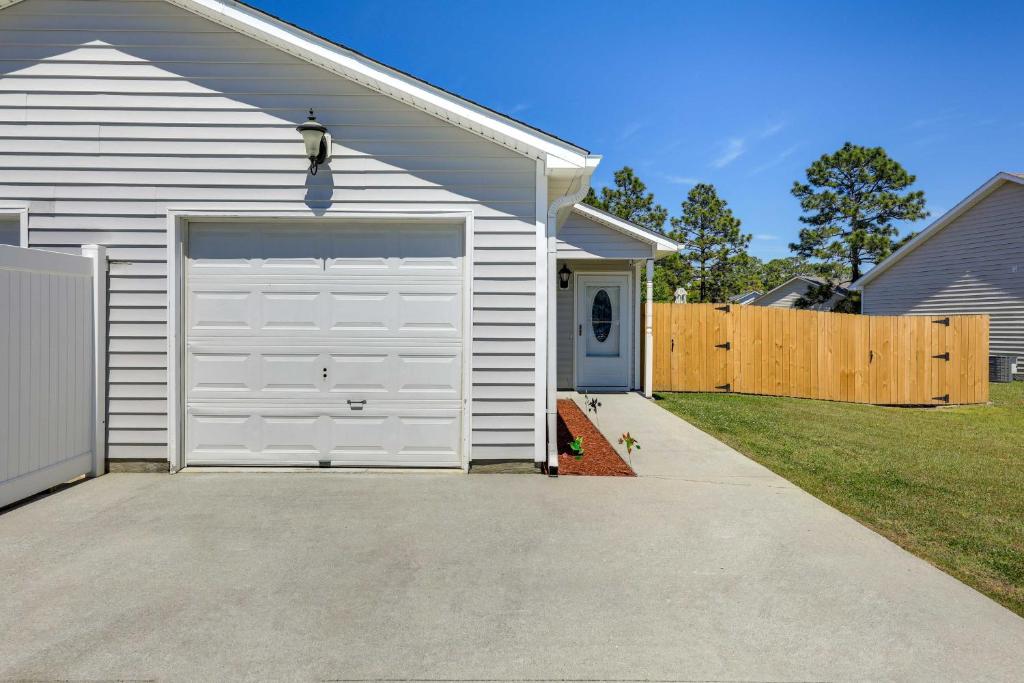 a white house with a garage with a driveway at Updated Hubert Vacation Rental 5 Mi to Beaches! in Swansboro