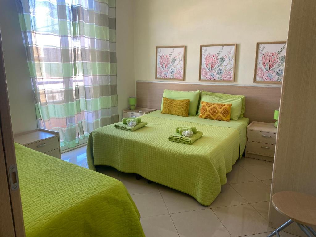 a bedroom with two beds with green comforters at B&B del centro storico *** in Rosolini