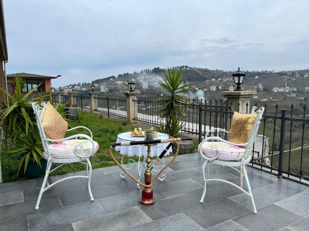 un patio con 2 sillas y una mesa en el balcón en Villa trabzon en Çağlayan