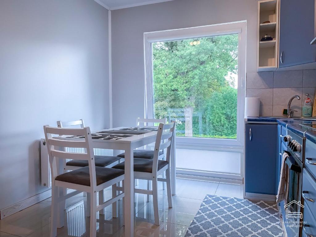 a kitchen with a table and chairs and a window at Apartamentai Biržuose, double bedroom and single bedroom Apartments in Biržai