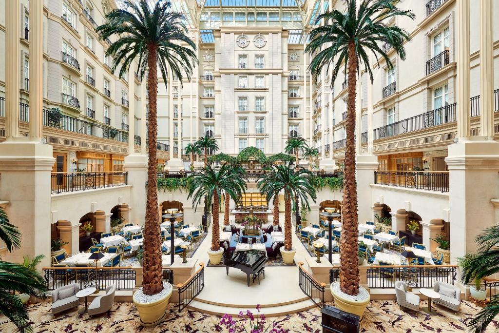 une image d'un hall d'hôtel avec des palmiers dans l'établissement The Landmark London, à Londres