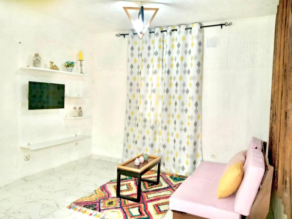 a living room with a pink couch and a table at Gêna house in Douala