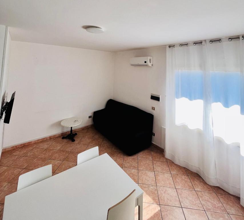 a living room with a black couch and a window at CANNONHOUSE La Pavoncella Rosa in Bari Sardo