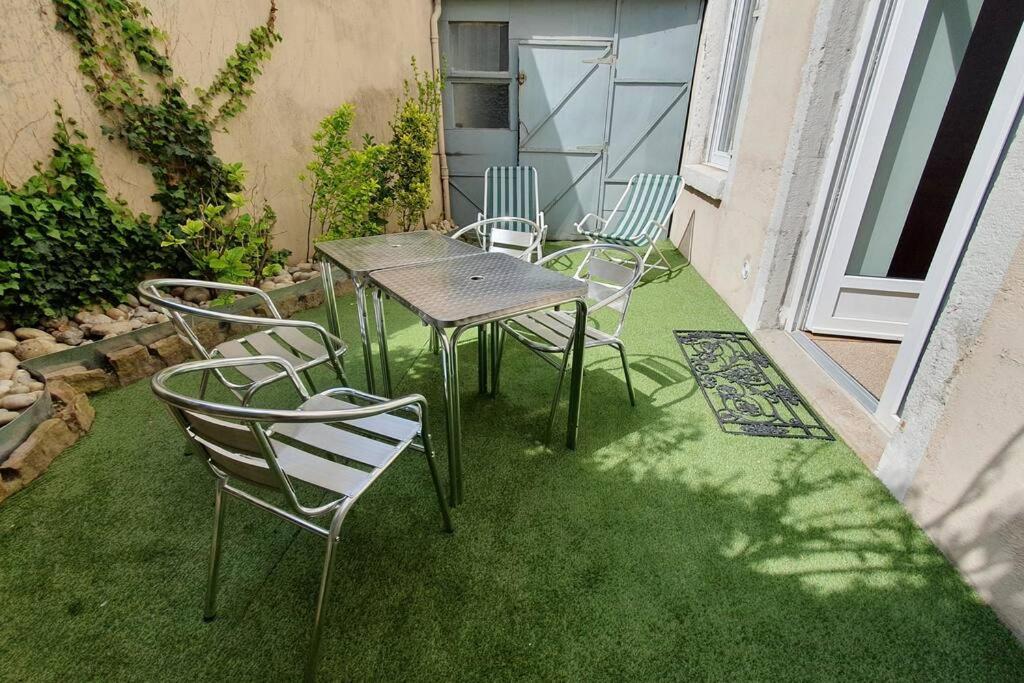 eine Terrasse mit Stühlen und einem Tisch auf dem Rasen in der Unterkunft Classé 4 étoiles - Cybèle - Centre ville 2 Chambres, cour privative et Garage in Vienne