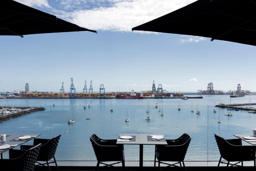 Blick auf einen Hafen mit Tischen und Booten im Wasser in der Unterkunft Silken Saaj Las Palmas in Las Palmas de Gran Canaria