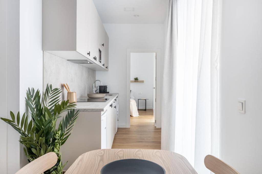 uma cozinha com armários brancos e uma mesa de madeira em Líbere Ciudad Real em Ciudad Real